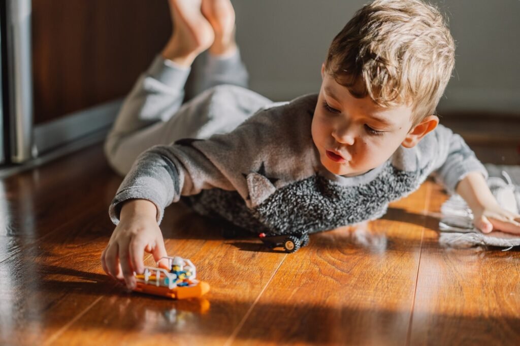 Young child playing with cars on a hardwood floor