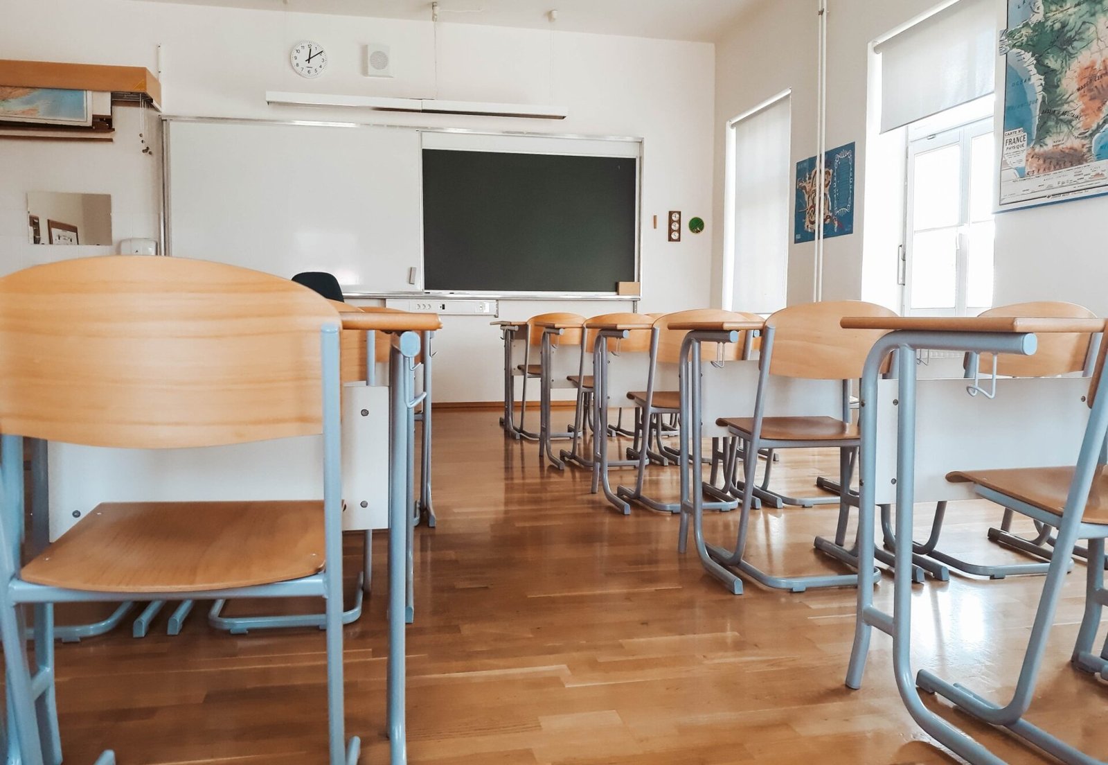An empty classroom with wooden chairs and a blackboard.